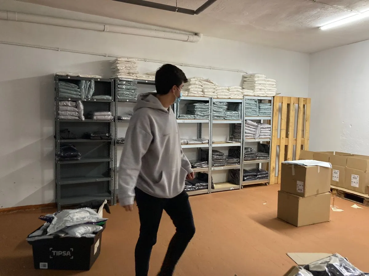 Un chico en el almacén, entre estanterías y cajas
